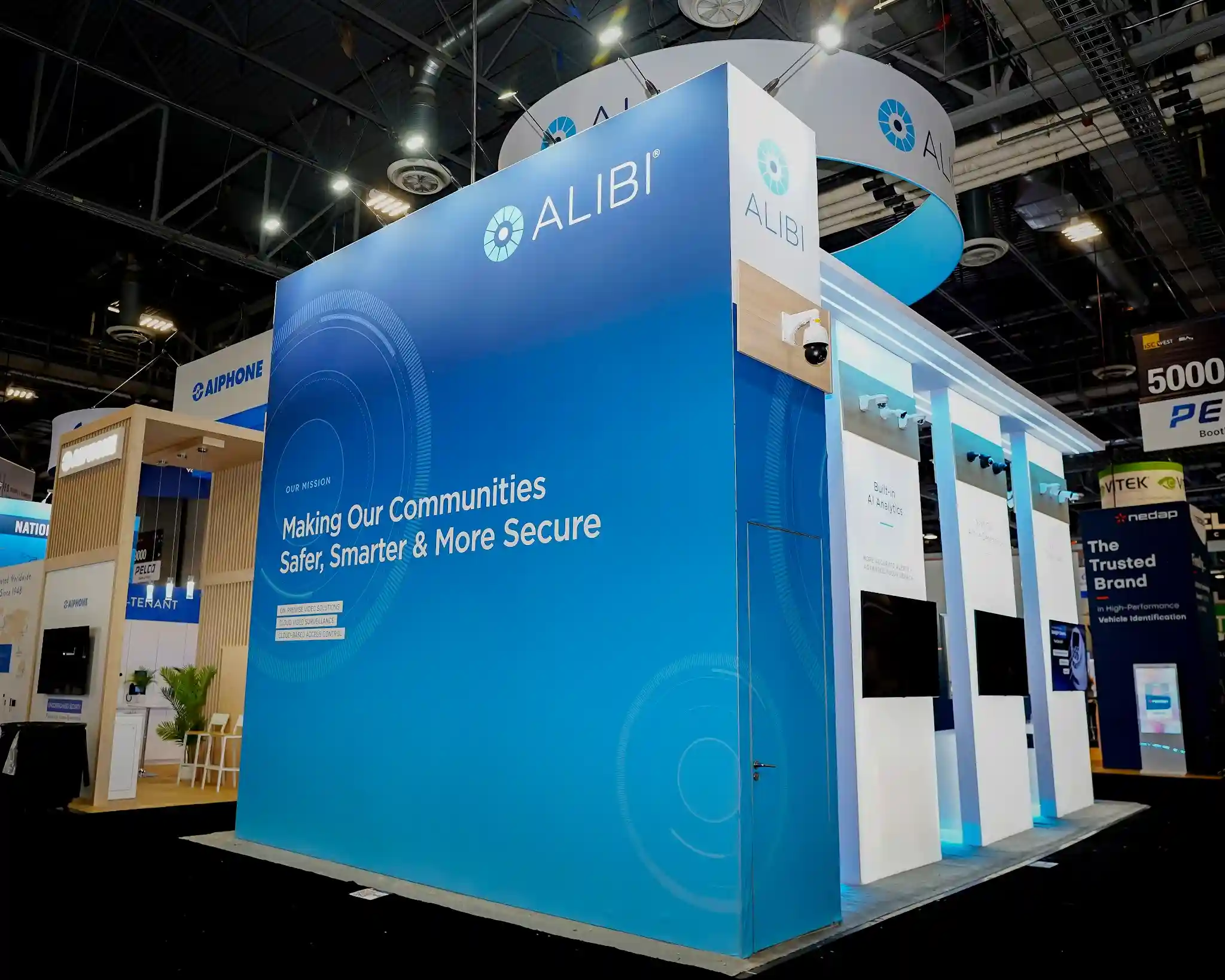 Side angle showing booth height and architectural depth, transition from blue mission wall to white interior bays, blue LED floor lighting against dark carpet