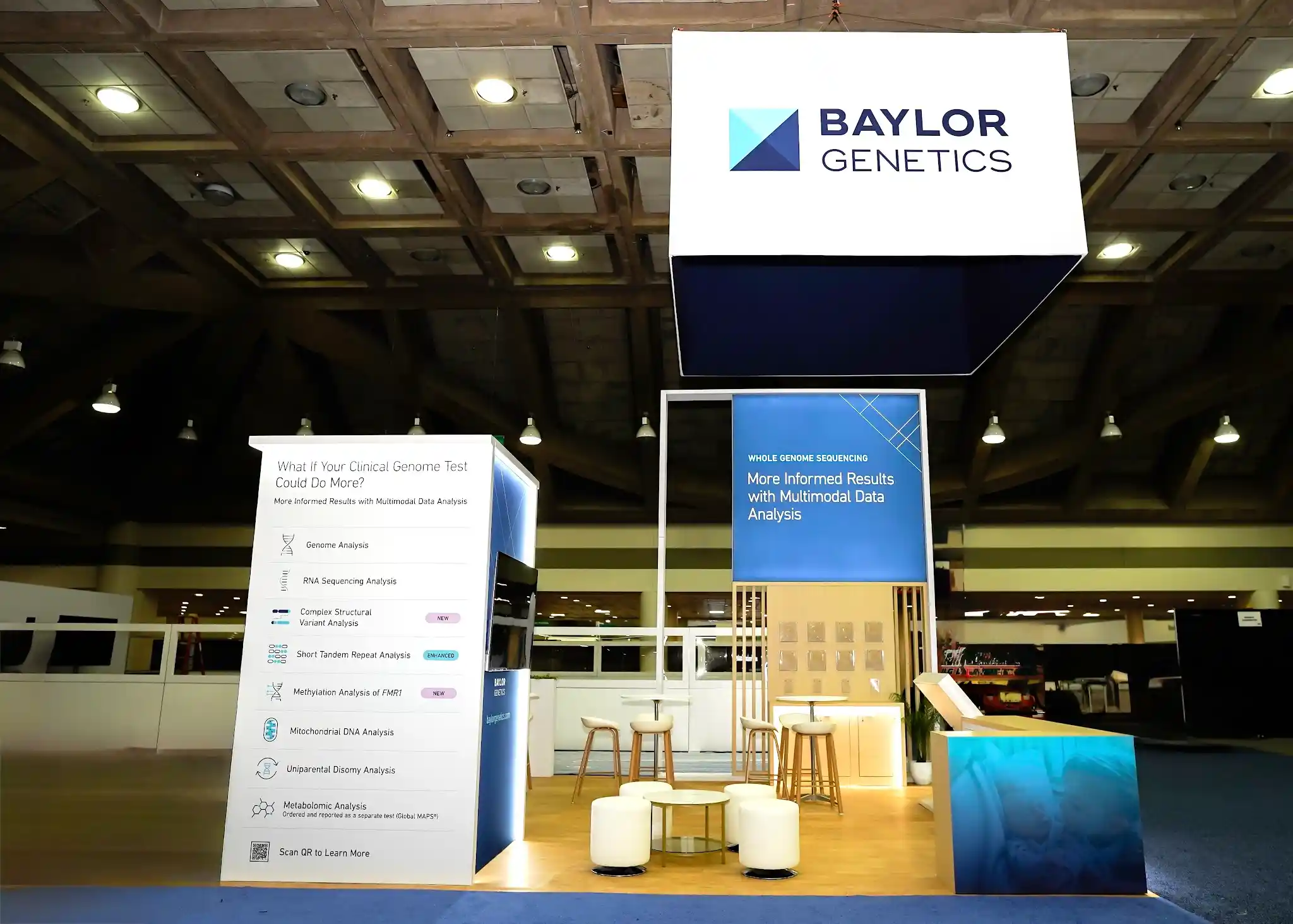 Frontal view of Baylor Genetics booth showing detailed multimodal services menu panel with EXPANDED and NEW badge callouts for WGS testing offerings, bar-height meeting tables with cylindrical ottomans, WGS tower with natural wood slat cladding, and Baylor Genetics logo signage above