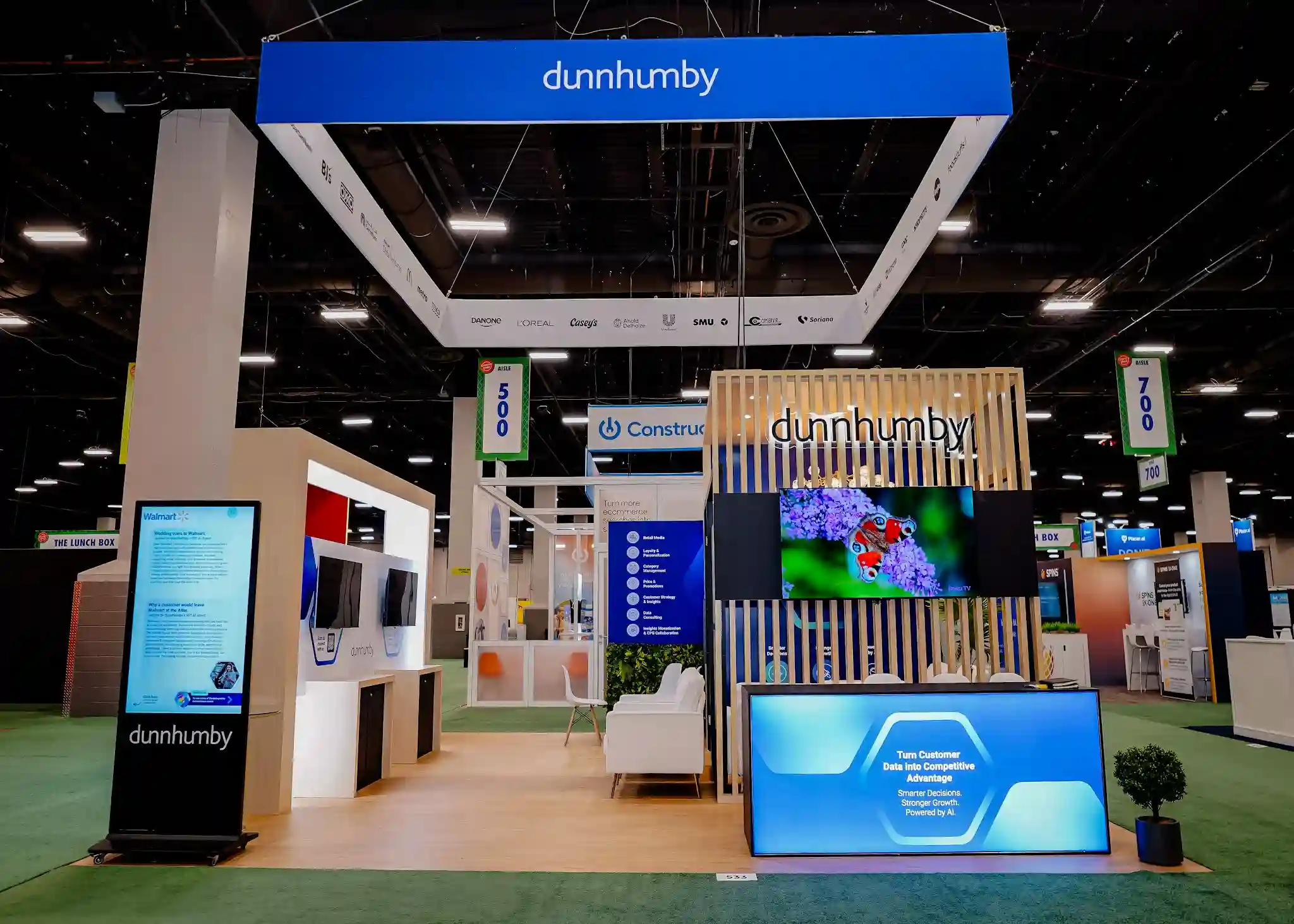 Frontal entrance view with digital case study kiosk showing Walmart Building Trust in Private Brand story, reception counter, and butterfly nature display on monitor