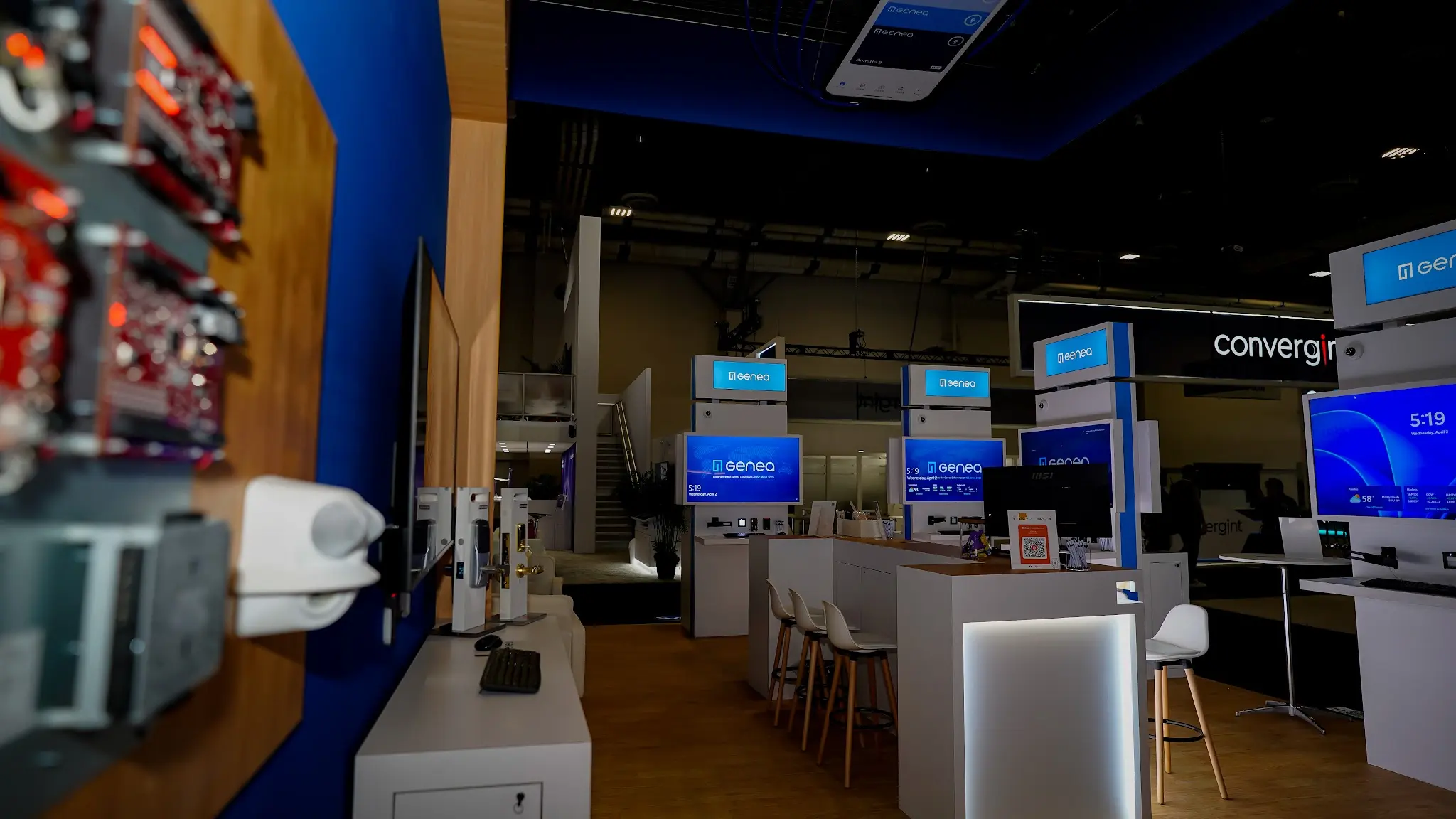 Convergint partnership area with backlit black header panel, Hardware Wall featuring wood panel with exposed circuit boards and security controllers, white storage cabinet base with integrated cable management