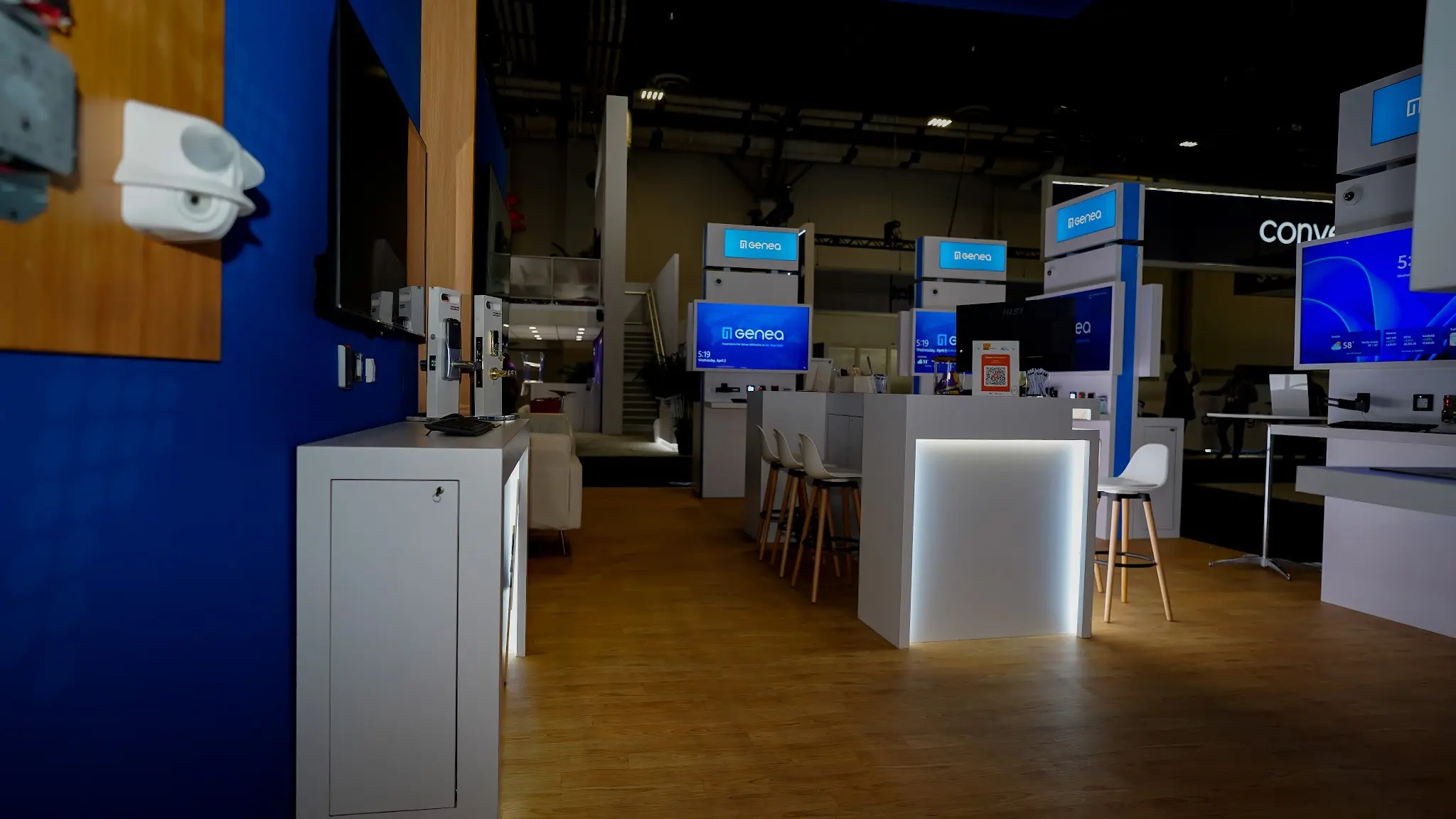 Moody perspective shot showing internal LED lighting in counters and kiosks, white bar stools and distant white sofa, multiple blue-themed screens creating cohesive tech ambiance