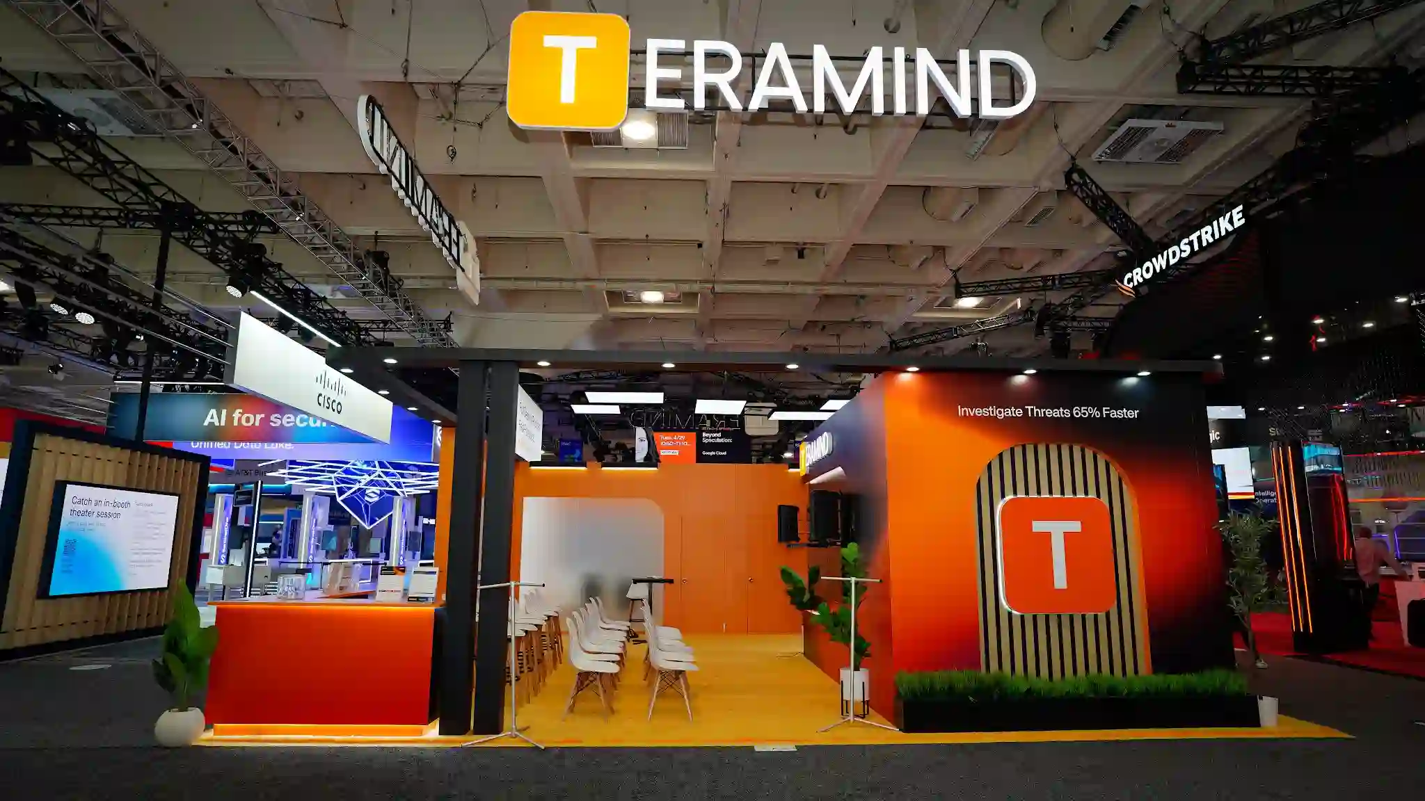 Front entrance view of the Teramind booth at RSA Conference 2025 showing the dramatic blonde wood slat arched portal gateway as the primary architectural feature framing the main entrance, Solving for the human element tagline prominently displayed with Solving in orange and the rest in white text against the dark charcoal fascia above the arch, TERAMIND three-dimensional logo sign with golden-T icon suspended overhead, burnt-orange accent panels flanking the entrance, amber carpet flooring leading into the booth interior, LED ceiling panel tiles visible through the arch providing bright ambient lighting, product messaging panels with Investigate Threats 65 Percent Faster and Every Action Every User Full Attribution visible on interior walls, demo kiosk stations visible deeper inside the booth, tropical green plants at the entrance adding organic warmth, RSA Conference attendees approaching the booth entrance