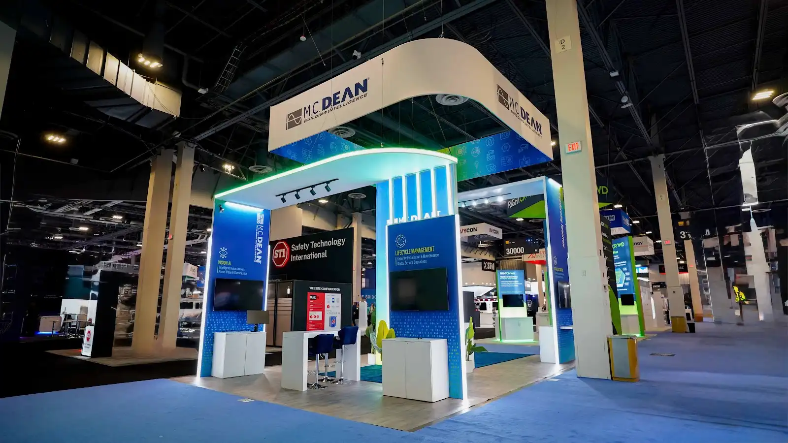 M.C. Dean booth front-right view showing dramatic arched entry portal with cyan LED tube columns and Transforming Tomorrow vertical column text at ISC West 2026