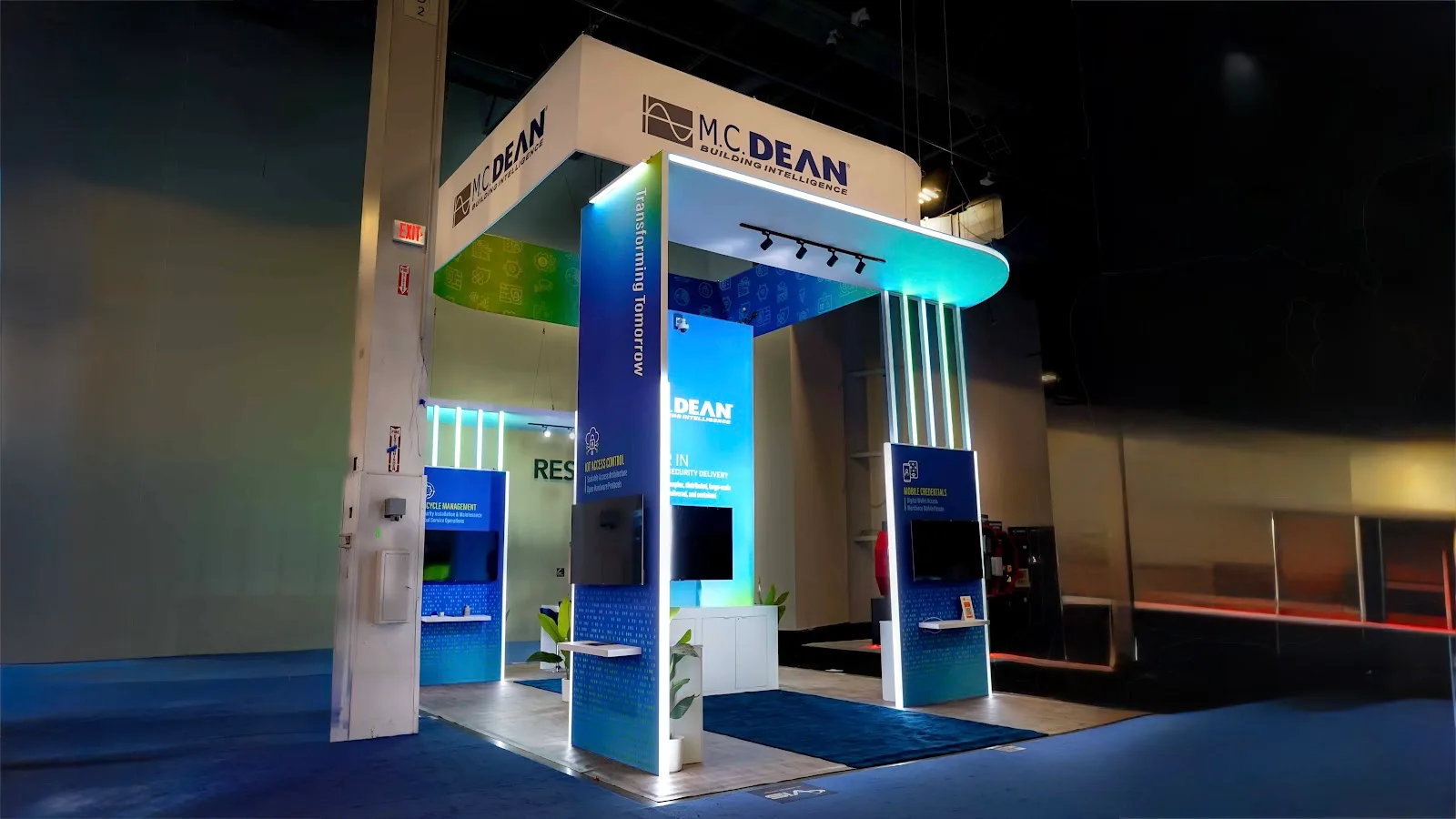 M.C. Dean booth front-center head-on view of arched portal entry with cyan LED tube columns at ISC West 2026
