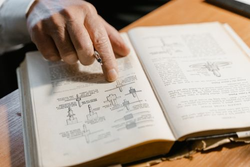 Exhibitor reviewing a thick trade show exhibitor manual with highlighted deadline sections Exhibitor reviewing a thick trade show exhibitor manual with highlighted deadline sections