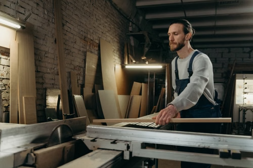 Trade show booth builder fabricating custom exhibit components in a workshop, using woodworking equipment to prepare booth structures and display elements.