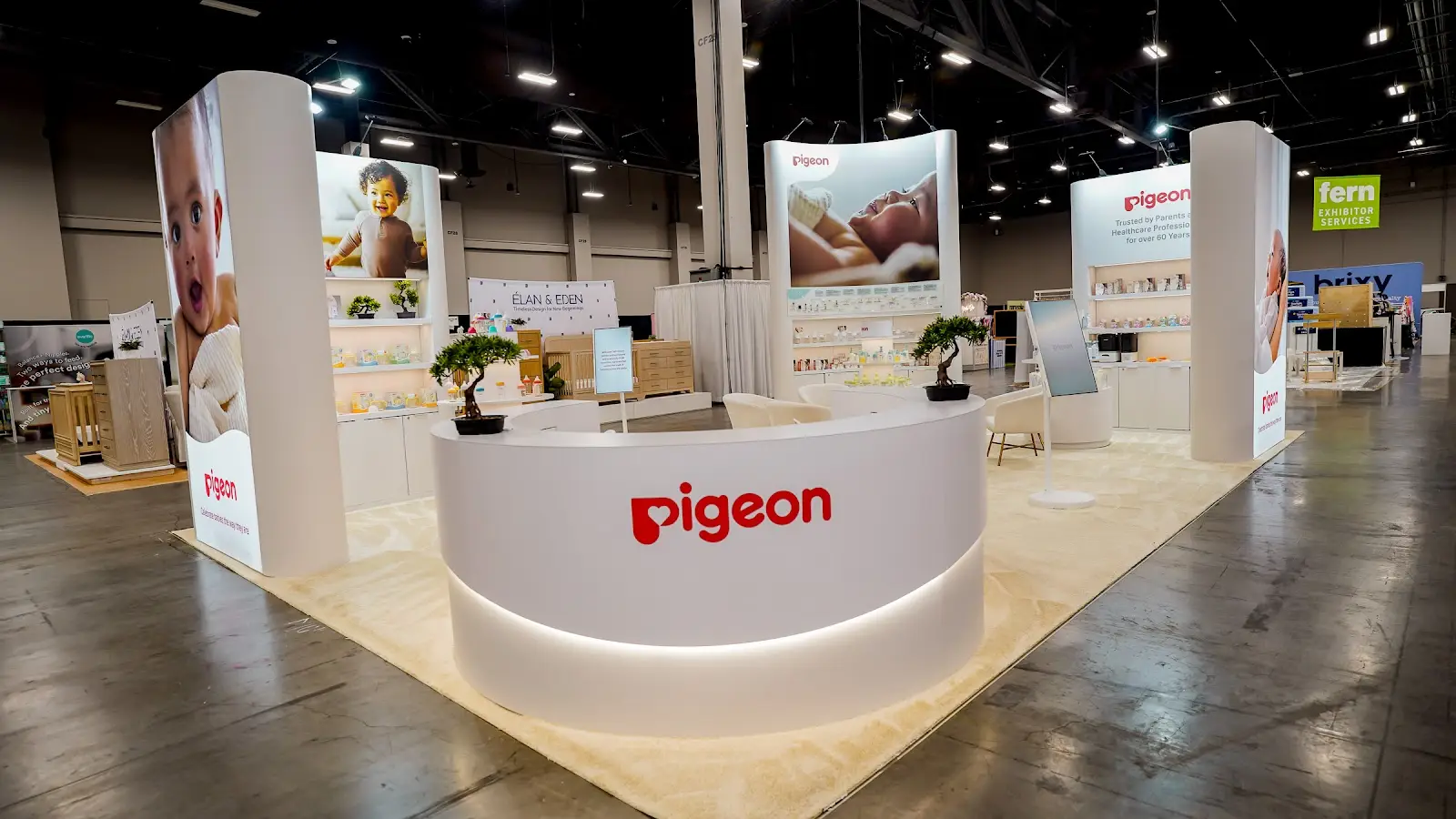 Pigeon heritage wall and product display at ABC Kids Expo 2026 showing curated brand storytelling panels alongside precisely arranged product collections on white shelving, communicating the brand's 67-year history and research-backed development philosophy