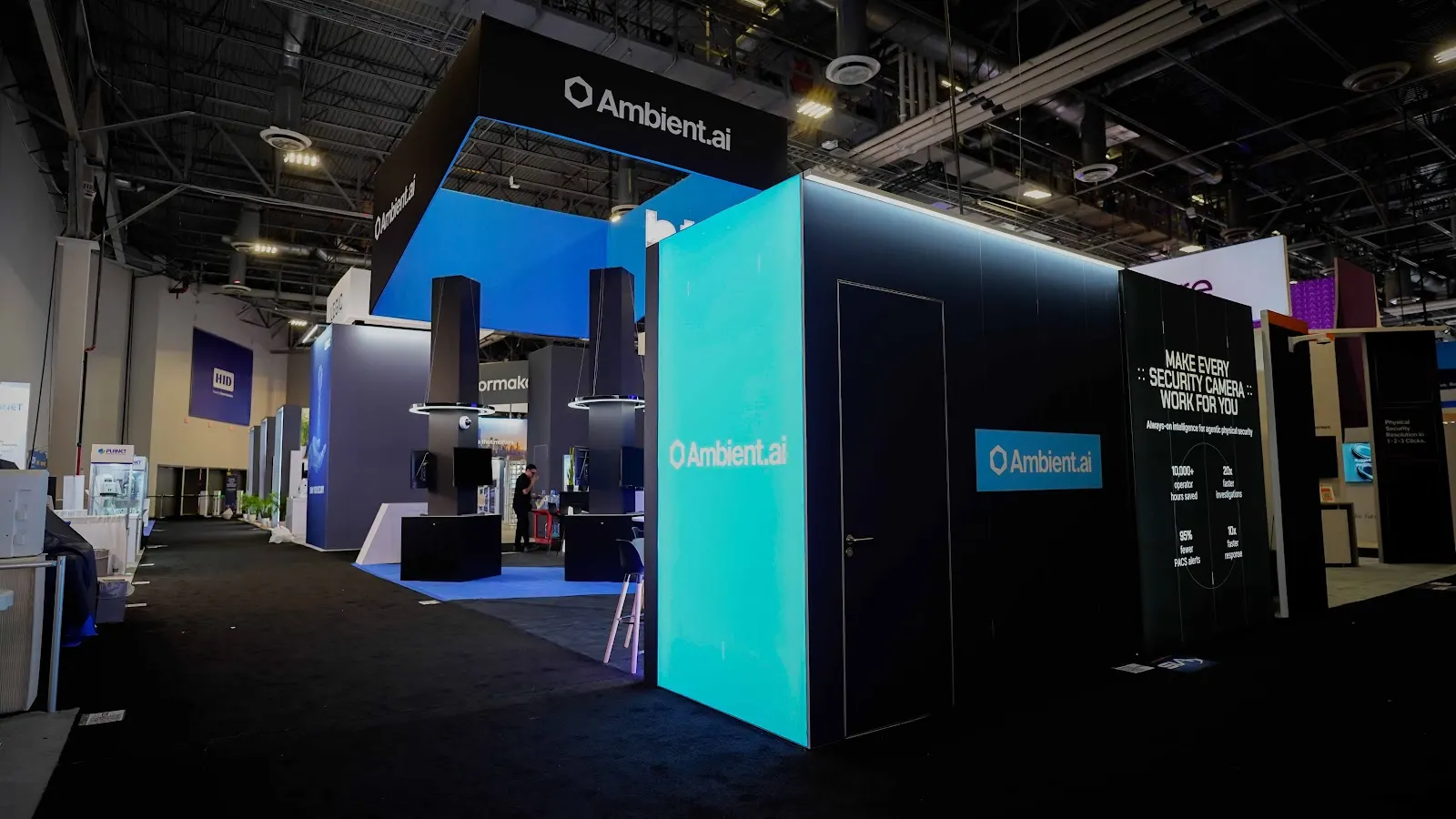 Black and blue Ambient.ai trade show booth at ISC West 2026, with screen-led displays replacing the product tables typical of the security show floor