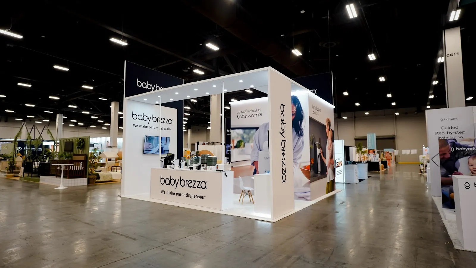 Baby Brezza modern white island booth at ABC Kids Expo 2026 seen from a second angle, showing the clean structural forms