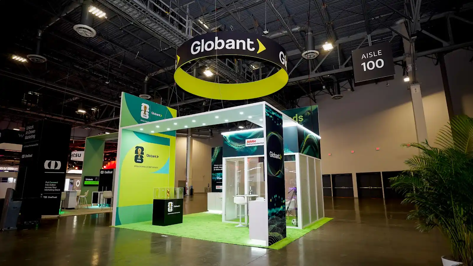 Globant custom island booth at Adobe Summit 2026 viewed from a second angle, showing the open structure and green architectural elements
