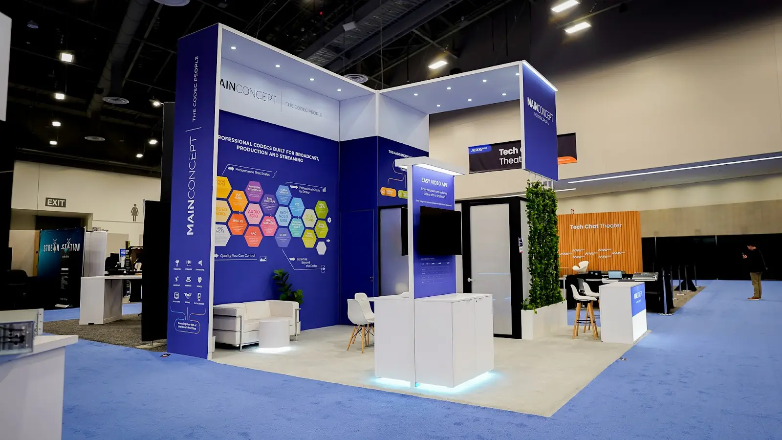 MainConcept blue and white island booth at NAB Show 2026 secondary angle showing the technical precision zone with open layout and structured product demonstration areas