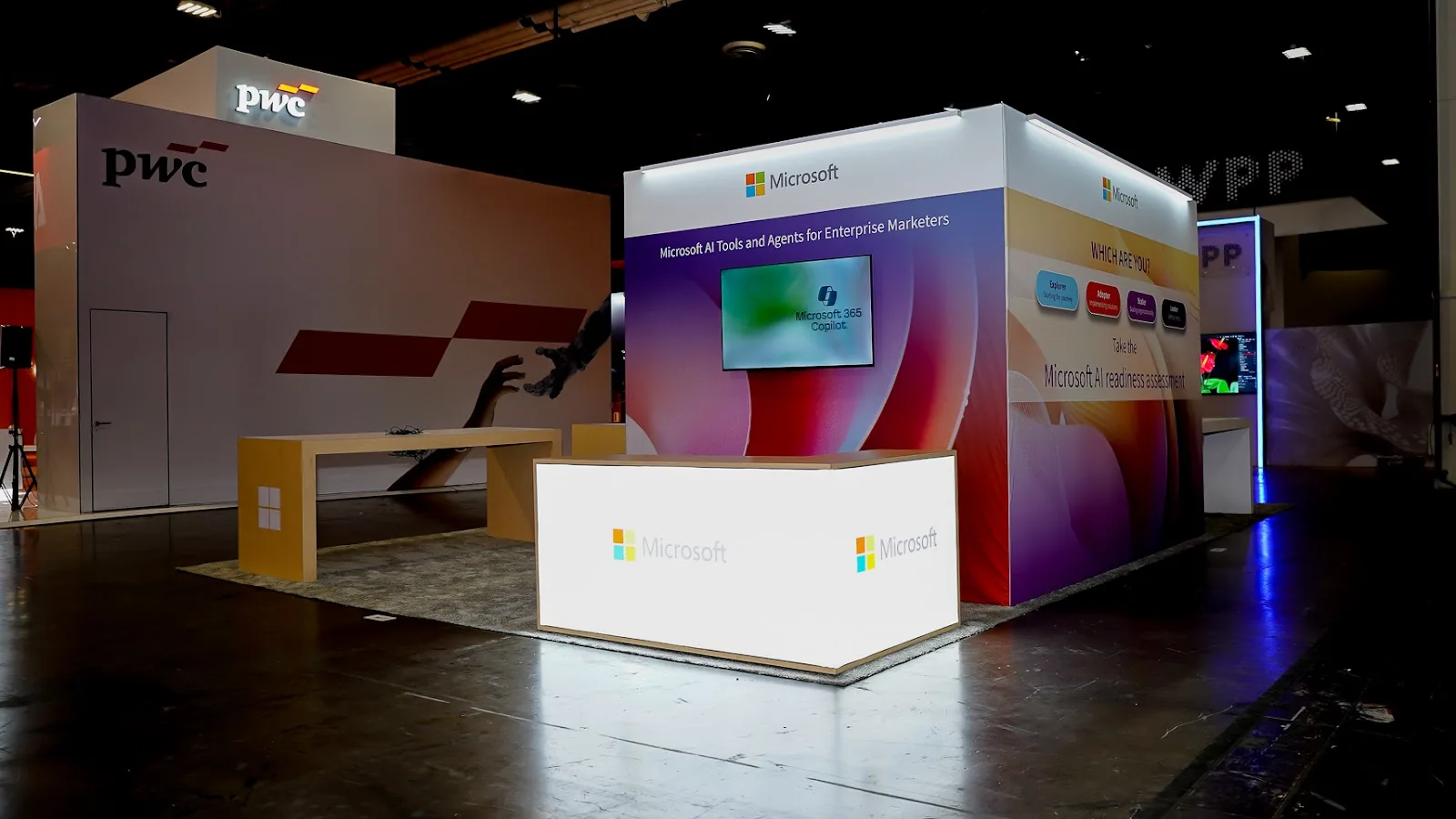 Corporate exhibits at Adobe Summit 2026 at the Venetian Expo, with the Microsoft booth alongside the neighbouring PwC stand on the partner floor