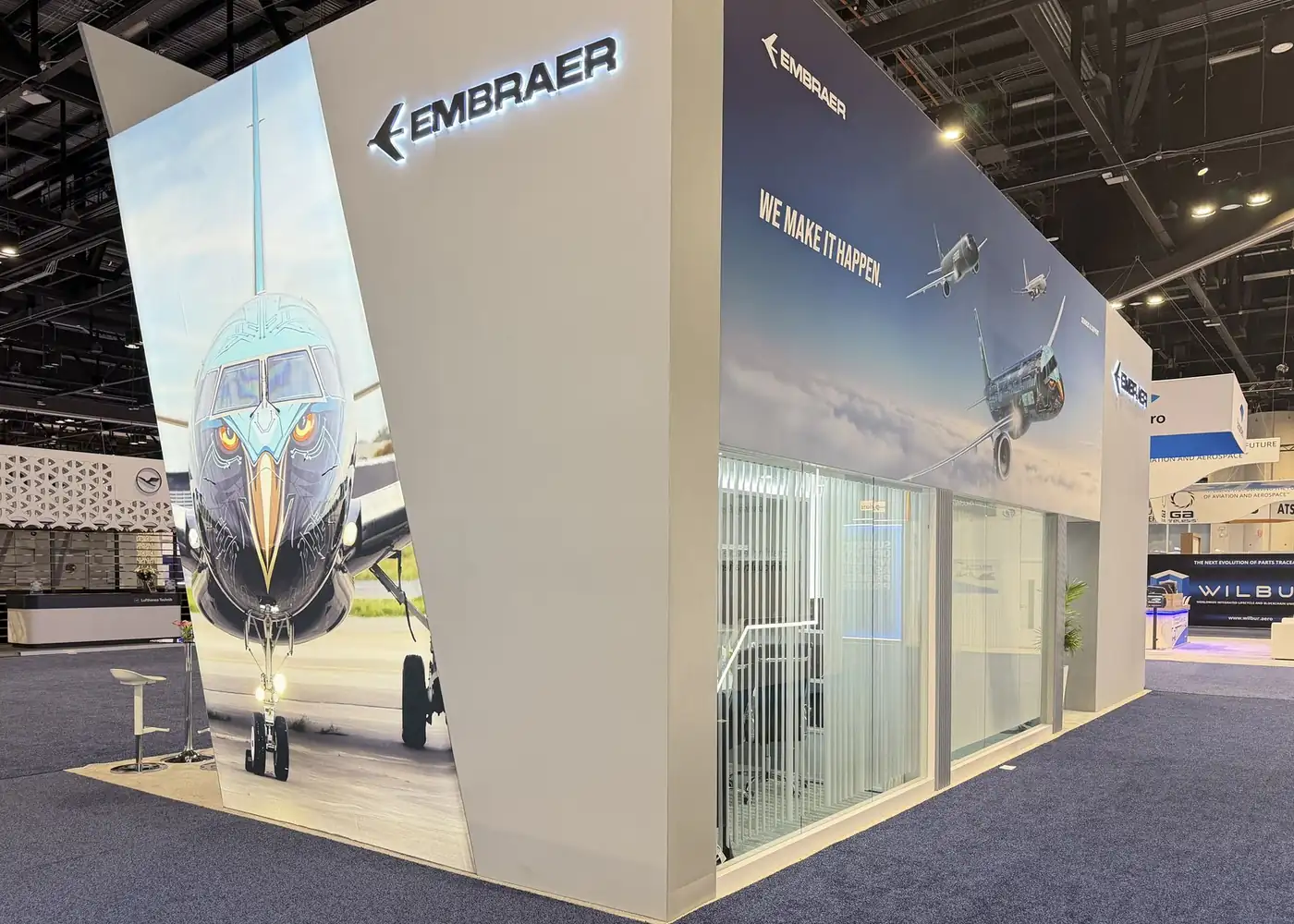 Close view of the eagle-nose E-Jet graphic wall and We Make It Happen mural at the Embraer booth, MRO Americas 2026
