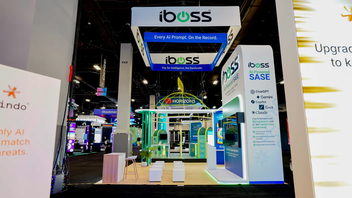 Aisle view of the iboss booth at Black Hat USA 2026 with the hanging sign reading Every AI Prompt On the Record and a pillar listing ChatGPT, Gemini, Copilot, Grok and Claude