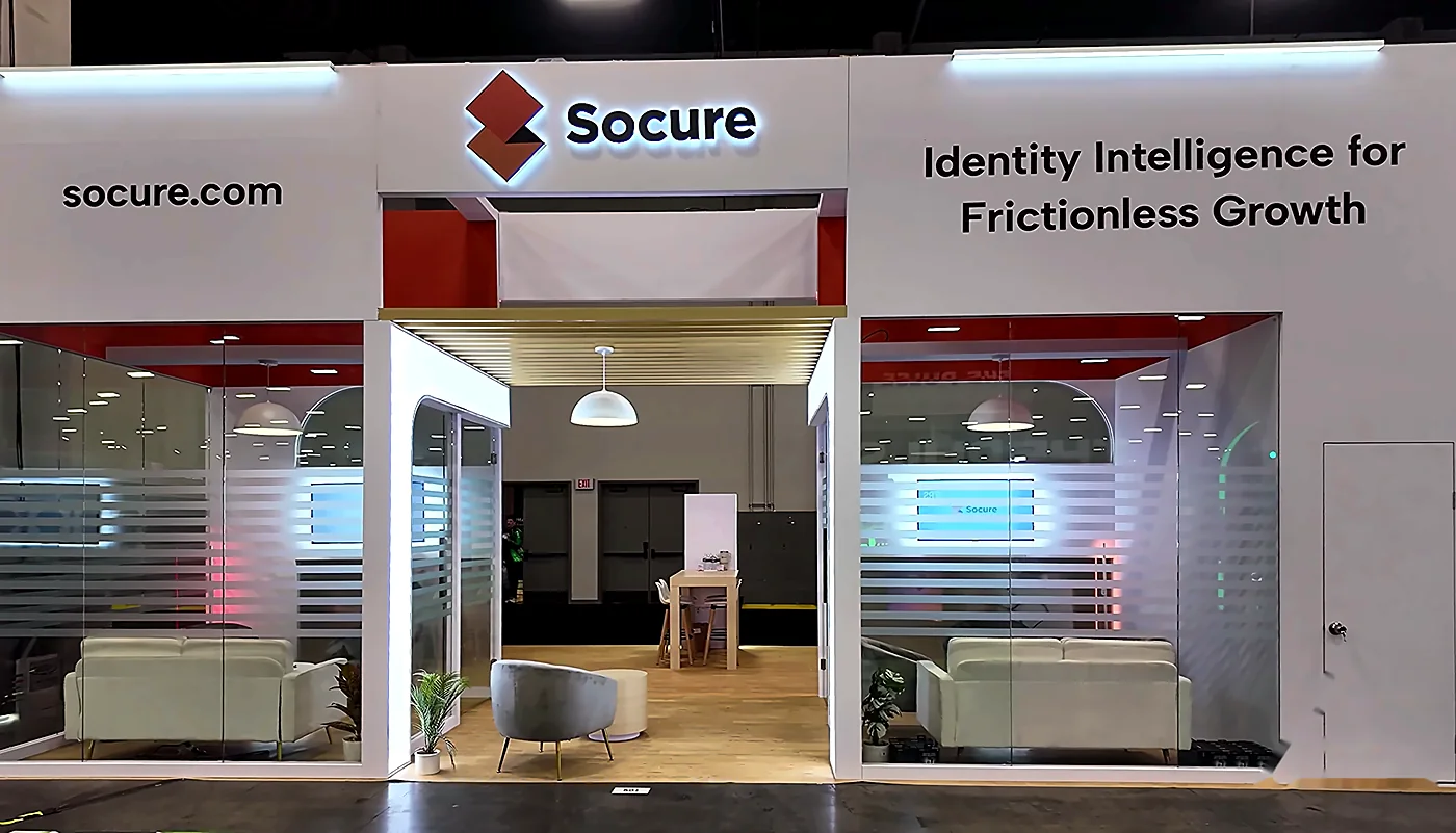 Rear elevation of the Socure 20x30 booth at Fintech Meetup 2026 with socure.com and Identity Intelligence headers, wood-slat canopy and lounge seating