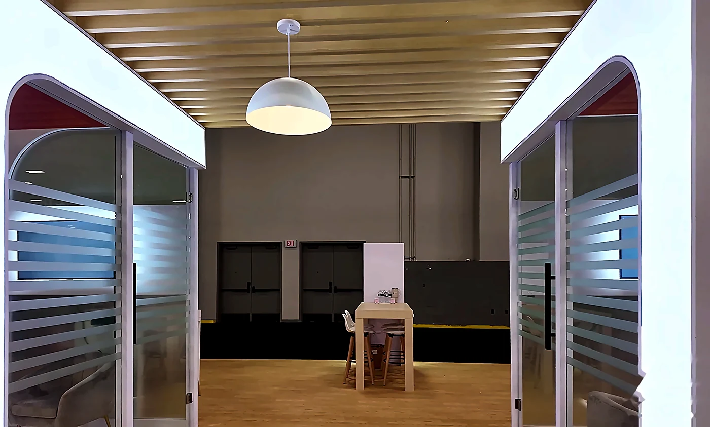 Interior of the Socure 20x30 booth at Fintech Meetup 2026 looking through the arched openings at the wood-slat canopy, pendant light and meeting table