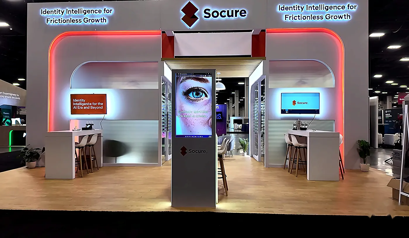 Front view of the Socure 20x30 booth at Fintech Meetup 2026 with the central digital kiosk playing brand video, side monitors and Socure header
